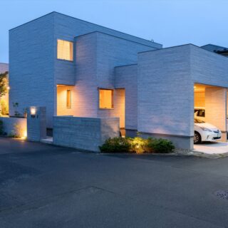 外観夕景。庭や擁壁の植栽を照らす照明が美しい。駐車場や室内からの光の漏れ方とあわせて総合的に考えられていることがよくわかる