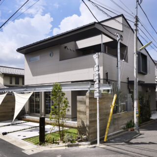 写真中央、木目の塀の隣に写っているのは防災備蓄倉庫の壁。庭にかかったパーゴラ風の鉄骨梁はタープをかけるなどして庭を彩ることができる。同時に、災害時はここにテントを張って備蓄品を並べるなど、地域の人と助け合える場にすることも想定
