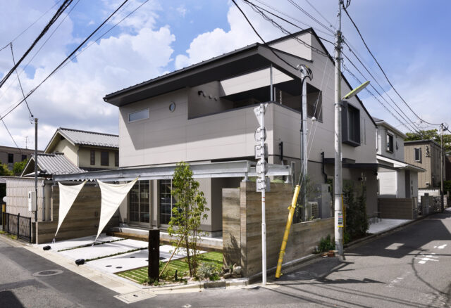 写真中央、木目の塀の隣に写っているのは防災備蓄倉庫の壁。庭にかかったパーゴラ風の鉄骨梁はタープをかけるなどして庭を彩ることができる。同時に、災害時はここにテントを張って備蓄品を並べるなど、地域の人と助け合える場にすることも想定
