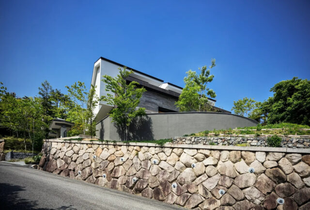 外観。敷地が広いため、低い塀を立てて家のエリアを区切った。塀の裏には「丘の庭」がある。リビングから丘の庭を見たとき、さらにこれだけの敷地が続くおかげで、周辺からの視線は気にならない
