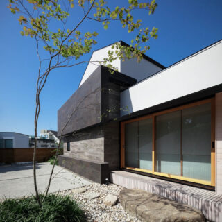 和室の庭。画像右、木製サッシは和室のもの。ごろた石を敷いた和庭園には、植栽した紅葉の影が美しく落ちる
