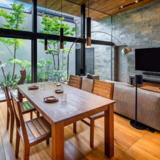 ダイニングセットはAさまの手持ちの家具で、チークでつくったオーダー品。テレビ裏の石壁は中庭まで伸び、外まで伸びた天井とともに中庭との一体感を強調。中庭の奥が壁で囲われていることで「あの壁までがプライベートな1つの空間」と感じられ、一体感と安心感が生まれる