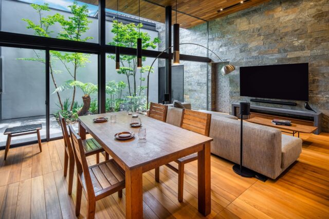 ダイニングセットはAさまの手持ちの家具で、チークでつくったオーダー品。テレビ裏の石壁は中庭まで伸び、外まで伸びた天井とともに中庭との一体感を強調。中庭の奥が壁で囲われていることで「あの壁までがプライベートな1つの空間」と感じられ、一体感と安心感が生まれる