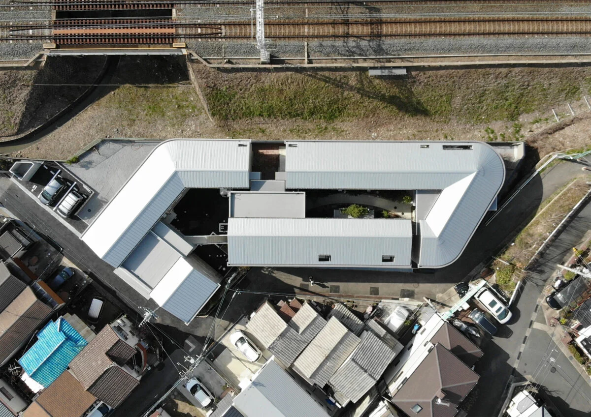 線路脇の古いアパートが２棟建っていた横長の敷地を、取り囲むように３棟の建物で構成。庭や駐車スペースなどで敷地を効率的に利用した。

