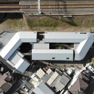 線路脇の古いアパートが２棟建っていた横長の敷地を、取り囲むように３棟の建物で構成。庭や駐車スペースなどで敷地を効率的に利用した。
