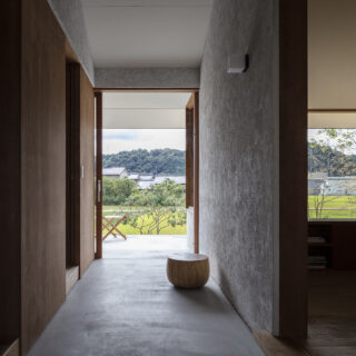 通り土間から見た南側の景色。玄関を入った時にこの風景が見えることで、その先の景色を期待させる。外の景色を最大限に楽しめるよう、南側の引き戸は全開放できるように設計された。外と中の連続性を感じられるように、通り土間の壁は外壁と同じ素材でできている
