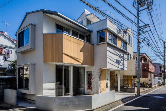 南西の角から家を見る。主に北側から受けるさまざまな制限に合わせて屋根の高さや形状を計画。外観を見ると、西側半分と東側半分で家の高さも張り出し方も異なるため、分断されているような印象も受ける。西側の大きな開口はリビング。窓の外には要望から小さな庭を計画
