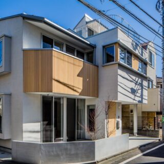 南西の角から家を見る。主に北側から受けるさまざまな制限に合わせて屋根の高さや形状を計画。外観を見ると、西側半分と東側半分で家の高さも張り出し方も異なるため、分断されているような印象も受ける。西側の大きな開口はリビング。窓の外には要望から小さな庭を計画
