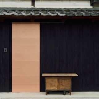 エントランス。玄関ドアは銅葺のものをオリジナルで製作。黒い外壁との対比が美しい。外壁は、一般的に外壁の下地材として使われるものを塗装して使用。とても幅が細い素材で表情が豊かだ。ドア右の箱は、お施主様所有のもの。宅配ボックスとして使用されている
