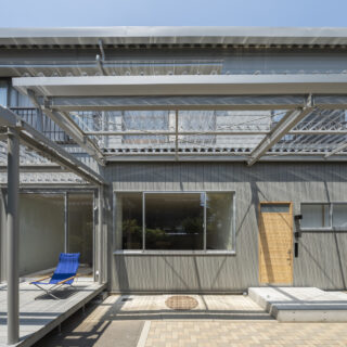 リノベーション後の『飯島の家』。外壁は上品なグレーで塗装され、庇も透過性のある屋根材に替わり、明るく軽やかな印象に一変。木製の玄関ドアは杉でつくり、玄関まわりの外壁もグレーに塗装した杉を使用。木の温かみも感じられるナチュラルモダンな外観に生まれ変わった

