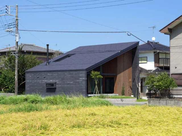 西側の田園から見た外観。狭い生活道路に面している西側にはあえて大きな窓を設けず、まるで隠れ家のようだ。西側に流れる屋根としたことで高さが抑えられ、道路を歩く人に圧迫感を与えていないことがよくわかる
