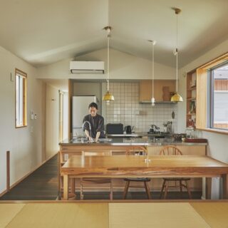 タイル張りがかわいい子世帯のキッチン＆ダイニング。キッチンは小嶋さん設計のオリジナル。ダイニングテーブルは杉の一枚板で造作した。真鍮のペンダントライトは小嶋さんが提案したもので、富山の職人さんの作品。手入れをすれば何十年も使えて、経年変化も楽しめる
