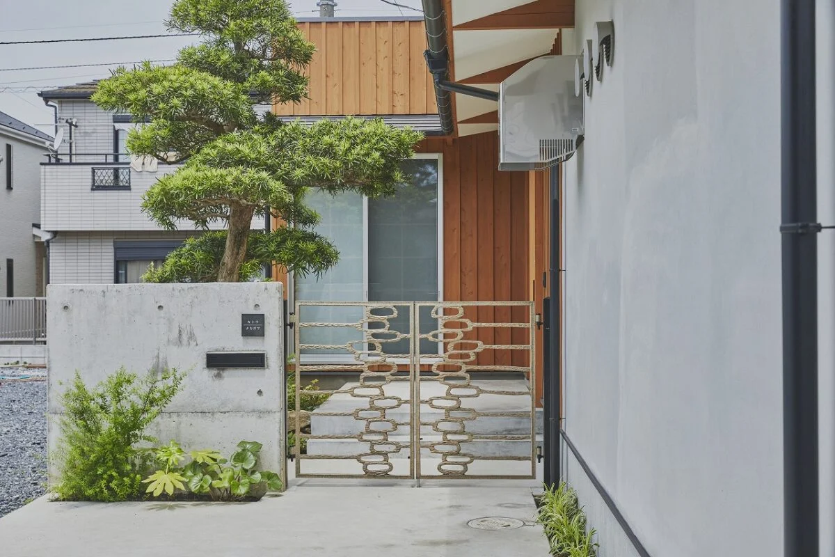 住宅玄関は店舗エントランスと反対側に設け、家族とお客様の動線をしっかりとセパレート。アーティスティックな門扉は建て替え前の家から受け継いだもの。立派な松も建て替え前の庭にあったものを植え替えている