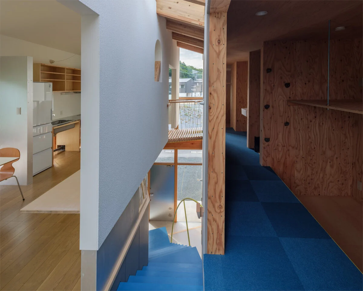 階段を中心に、2つの建物が繋がっていることがよく分かる。多様な空間であることを目指し、階段室を中心に3つのレイヤーで構成されている。リビングとダイニング側は白く清潔感があり、階段室は明るく、寝室がある右側は暗い洞窟のような落ち着いた空間となっている

