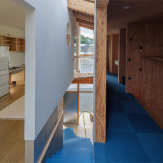 階段を中心に、2つの建物が繋がっていることがよく分かる。多様な空間であることを目指し、階段室を中心に3つのレイヤーで構成されている。リビングとダイニング側は白く清潔感があり、階段室は明るく、寝室がある右側は暗い洞窟のような落ち着いた空間となっている
