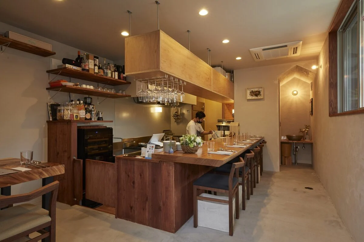 店舗は、ドアを開けると店内全てを見渡せるオープンな造り。イタリアの親しみやすいレストランをイメージし、床はモルタル、壁は炭を混ぜた自然塗料で温かな雰囲気に仕上げている。壁はK様一家が左官塗りに挑戦。手仕事のざっくりした風合いが味わい深い
