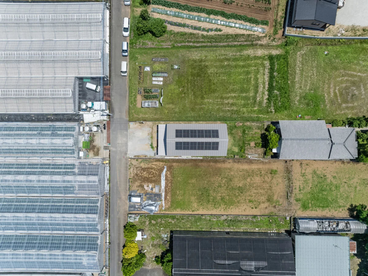 敷地全体をドローンで上空から撮影。敷地の両サイドはもともと田だった土地で、市街化調整区域内にあるため隣家が建ちにくい。左側に見えるのはミニトマトのビニールハウスだ
