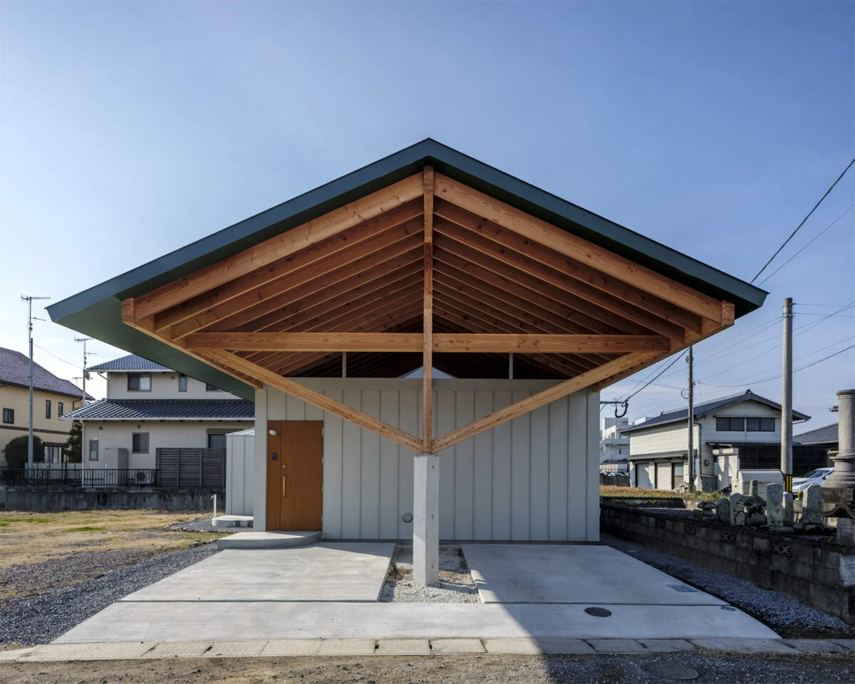 窓がない外観（正面）。切妻の大屋根が最大の特徴だ。柱を中央にすることで、雨で木の柱が傷まず、車の出し入れが容易になった。玄関ドアは外壁の縦のラインに合うように製作されている。木の梁に屋根が乗っているようなデザインにするため、軒の裏側も屋根と同じ色に塗装した
