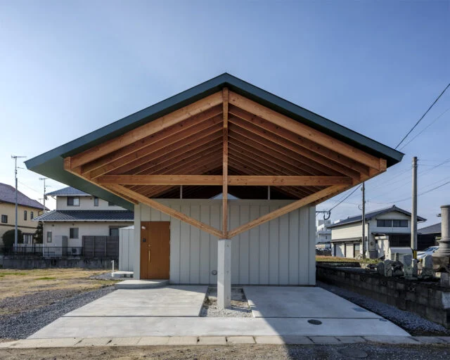 窓がない外観（正面）。切妻の大屋根が最大の特徴だ。柱を中央にすることで、雨で木の柱が傷まず、車の出し入れが容易になった。玄関ドアは外壁の縦のラインに合うように製作されている。木の梁に屋根が乗っているようなデザインにするため、軒の裏側も屋根と同じ色に塗装した

