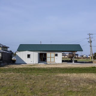外観（東側）。とても珍しい、大屋根の張り出し。駐車場をすべて覆っていることがわかる。　構造設計の専門家の協力を得て実現した。リビングの大きな引戸は全開することができる
