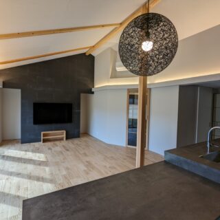 カラーを黒、白、木の３色で統一した、温もりの中にも落ち着きを感じさせるＬＤＫ。照明コンサルタントでもある寿有さんによって、全体は間接照明に。テレビボードの裏は、デッキなどの収納スペース。お子さんたちのおもちゃなども隠せるのだとか。
