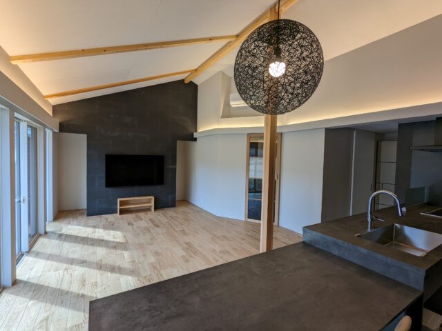 カラーを黒、白、木の３色で統一した、温もりの中にも落ち着きを感じさせるＬＤＫ。照明コンサルタントでもある寿有さんによって、全体は間接照明に。テレビボードの裏は、デッキなどの収納スペース。お子さんたちのおもちゃなども隠せるのだとか。
