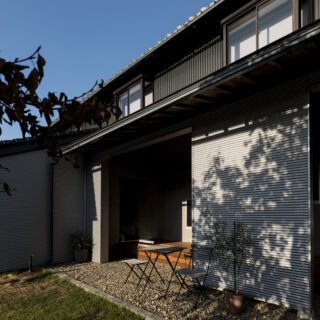 広い西側の庭から見たウッドデッキとピロティ（写真中央）。思い入れのある樹木が大きく生育し、美しい影を作る。後に増築されたエリアのため、2階部分は内外装ともに状態が良く、未改修だが違和感はない
