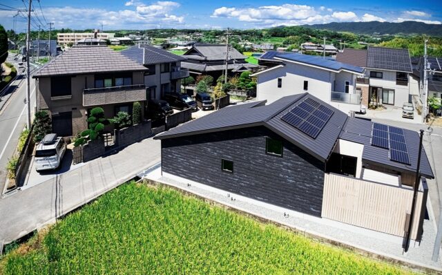 撮影：福澤　昭嘉
付近には住宅や田畑が点在する雰囲気の中に佇むH邸。屋根上の太陽光パネルで発電、蓄電池やエネファームも備え、災害時にも機能停止することがないようにした。