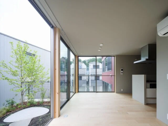 敷地北東に配置された104号室。北側と東側をL字形の専用庭に囲まれ、まるで戸建て住宅のような雰囲気。LDK南側の開口部からの風景は、まるで部屋が宙に浮かんだような不思議な印象をもたらす