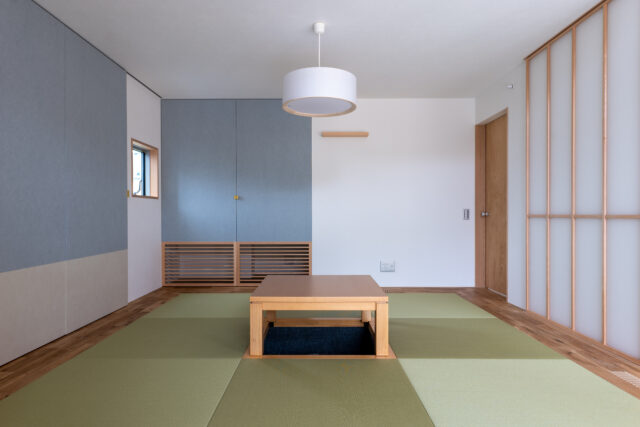 室内にある離れのような和室は、琉球畳と堀炬燵がある現代風。アクセントカラーのブルーの扉で仏壇を目隠し。床下エアコンからの暖気が、部屋の隅にあるガラリを通して室内を柔らかく暖めるという
