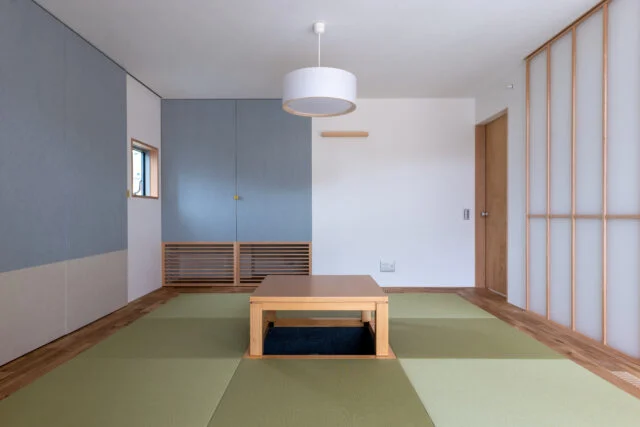 室内にある離れのような和室は、琉球畳と堀炬燵がある現代風。アクセントカラーのブルーの扉で仏壇を目隠し。床下エアコンからの暖気が、部屋の隅にあるガラリを通して室内を柔らかく暖めるという
