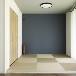 和室。濃紺の壁紙とグレーの天井により、シックな印象。収納の建具や畳はLDKにも調和するものを採用。LDKと一体とした際、一角に設けた子どもの遊び場にもなる
