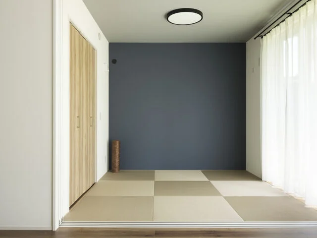 和室。濃紺の壁紙とグレーの天井により、シックな印象。収納の建具や畳はLDKにも調和するものを採用。LDKと一体とした際、一角に設けた子どもの遊び場にもなる