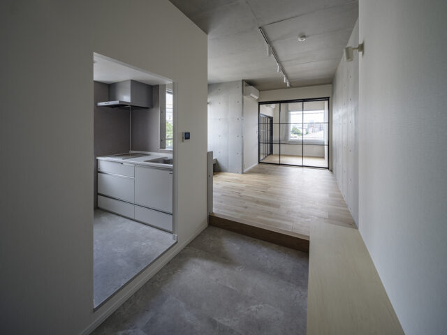 3階Ａタイプ・北東角部屋の住戸。エントランスの大きな土間は、ちょっと腰かけたり、モノを置いたりできるベンチ付き（写真右手前）。こうした造作家具や隣のキッチン（写真左）への動線の良さで、土間の活躍度が格段にアップする