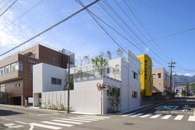 東側と北側が接道した敷地に立つ「LITTLEMATE」。鶴見岳から別府湾に向け傾斜した土地に合わせるように、東面ファサードを低く抑え、奥（西）へ向かって高くなるよう建物をレイアウト。周囲に圧迫感を与えないように配慮した
