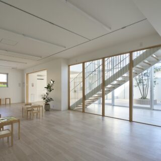 1階保育室から階段室、中庭を望む。保育室は東側一面がガラス張りになっていて明るく開放的。ぬくもりの感じられる木製サッシを採用している。外から、中庭→階段室→保育室とレイヤーにレイアウトすることで、プライバシーを確保すると同時に空間に奥行きが感じられる