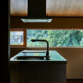 オリジナルでつくったキッチン。新たに設けた窓一面に緑が広がり、気持ち良く料理ができる。天井は杉板張り、壁は土塗りの左官仕上げで、この家の重厚感に負けない雰囲気の良い空間に仕上げている