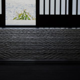 陰影の美しさは「窓辺の家」のテーマの1つ。玄関も日差しの入る明るい土間と薄暗い玄関ホールのコントラストが印象的。わずかな光で陰影が際立つ、なぐり加工の床も美しい
