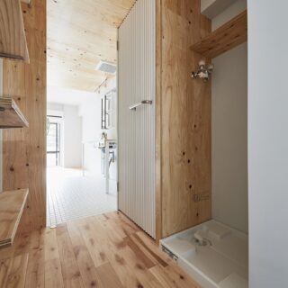 薄暗かった従前に比べ、光差し込む明るさと木に包まれる柔らかさともつ玄関ゾーンへと生まれ変わった。左側に可動棚とお手洗い、右に洗濯機置き場と収納を配置