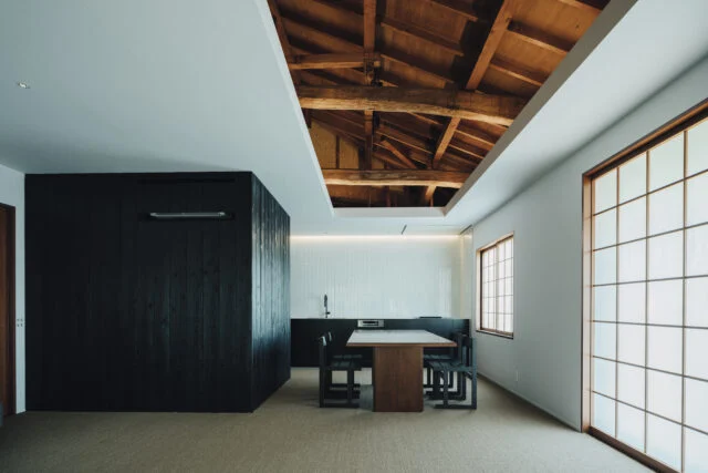 リビングから見たダイニング・キッチン方向。既存の天井の一部を開口部とし、立派な小屋裏を見せる。障子は既存の桟を活用。床は肌触りが良いサイザル麻カーペットを採用した