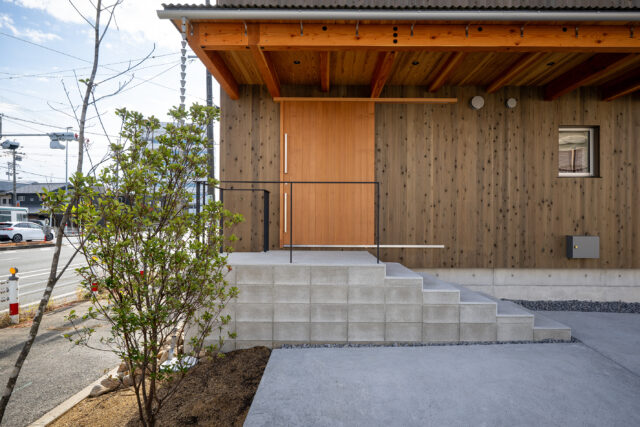 玄関は、コンクリート階段を上った先に。階段部分は建物本体と切り離すことで熱効率やシロアリ対策となるほか、異空間へ飛び込むイメージも。軒を深くとることで建物の構造面の補強にも。
photo：YASUO HAGIWARA