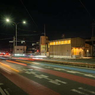 夜でもそれなりの交通量のある国道。室内の明かりが漏れるとともに、２階天井の現しの木組みの美しさがくっきりと見える。
photo：YASUO HAGIWARA