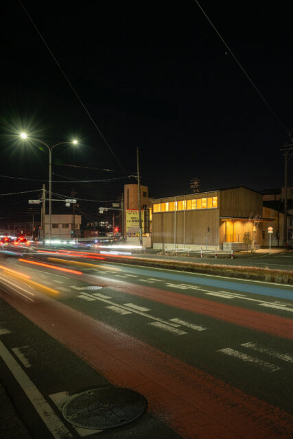 夜でもそれなりの交通量のある国道。室内の明かりが漏れるとともに、２階天井の現しの木組みの美しさがくっきりと見える。
photo：YASUO HAGIWARA
