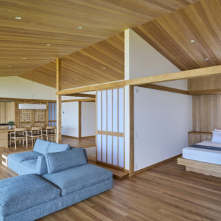 2階、リビングからキッチン方向を見通す。寝室に設けたエアコンの空気を部屋中に循環させられるよう、仕切り戸と天井までの間を空けた。また風の流れを計算し、高い断熱性も確保している。キッチンの壁面にもエアコンがあるが、寝室のものだけで十分涼しいという