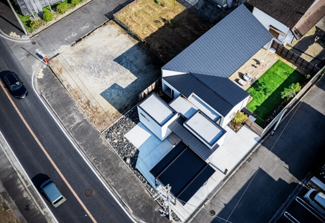 家を上空から見る。クローゼット、ゲストルーム、水回り、居住空間とエレメントごとに分け、それぞれを収めた箱を組み合わせたフォルム。それによってできた余白に大小２つの庭を計画した。黒い屋根部分が寛ぎの場。左に走る幹線道路から離し、プライバシーを確保した