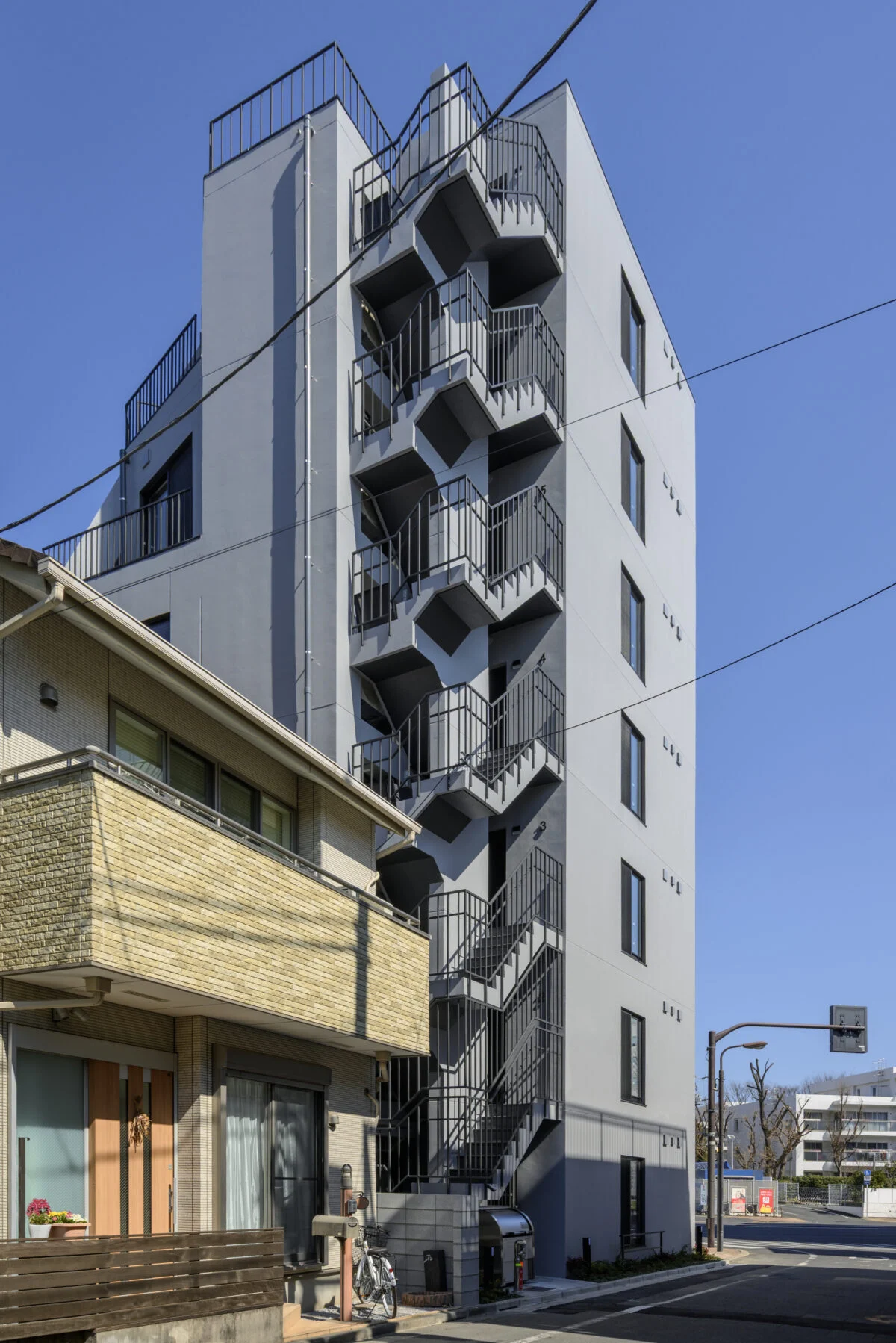 裏手にあたる南西側の屋外非常階段の踊り場に、法規的な主要な出入口（玄関）がある。