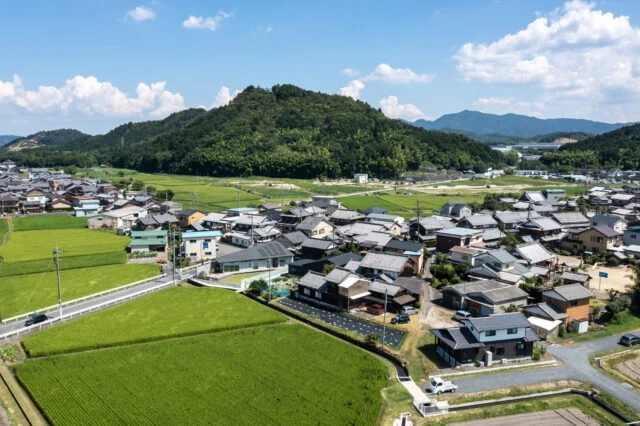 近江富士と呼ばれる三上山を背後に持つ、旧中山道の古い街並み。周辺環境との調和を考え、一部2階建てだが平屋のように見えるデザインを採用。近隣家屋でも採用されている切り妻屋根や、似た色を採用することで違和感や威圧感をなくした