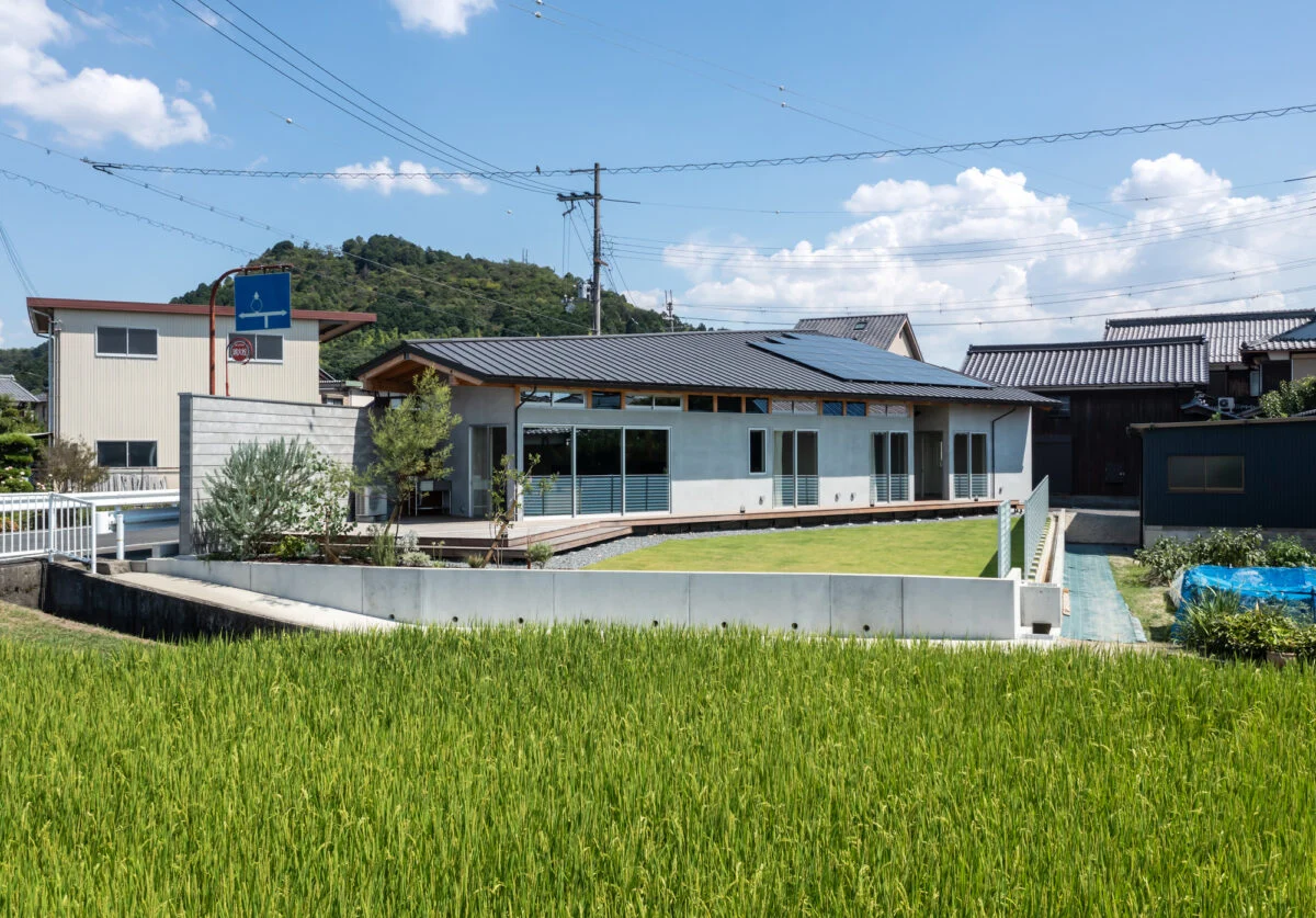 道路側の境界壁は敷地いっぱいに建てられ、視線をカットする役割も持つ。一方で手前の水田側は高低差もあるため、境界壁は設けていない。眼前に広がる水田の光景を楽しむためのプランだ。広い庭やウッドデッキでは、BBQやテントを張って楽しんでいるそうだ