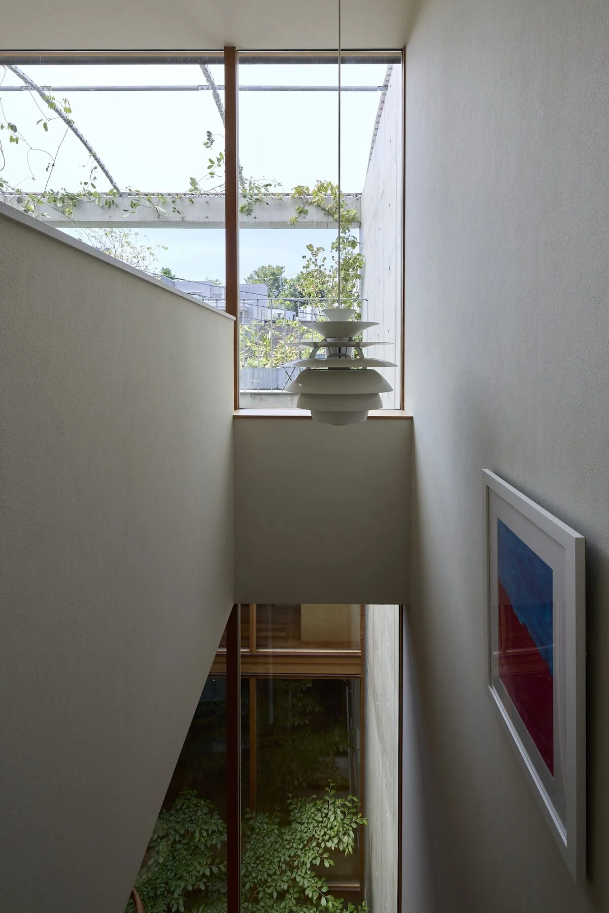 子世帯の階段からの眺め。正面に屋上庭園の緑、階下には中庭の緑が見え、階段も開放感がある