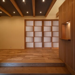 広くゆとりのある玄関ホール。主に来客用として使用される。右側の上部は吹き抜けで、明るく空間の広さを感じる。堂々とした玄関から続く場所として、違和感がない空間を意識した。右側の格子壁の奥には、家族用の玄関とシューズクローク。正面に見える造作の飾り障子が美しい